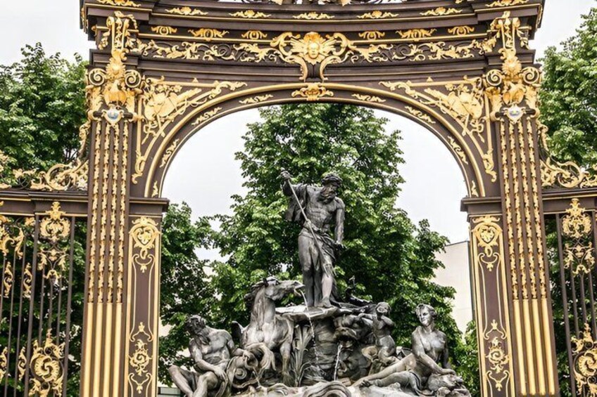 An ornate golden archway with a statue of a man holding a staff, surrounded by smaller statues. 4