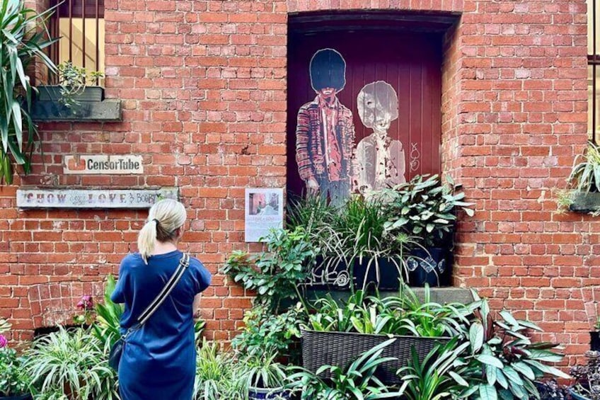 A brick building with a red door, a sign reading 'CensorTube,' and a mural of two figures. 5