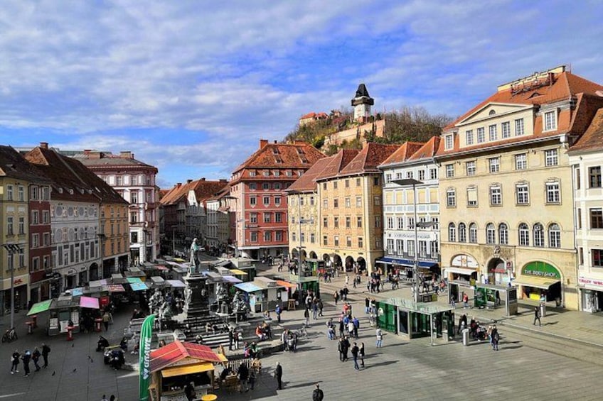 A bustling square with historic buildings, a central fountain, and outdoor cafes. 3