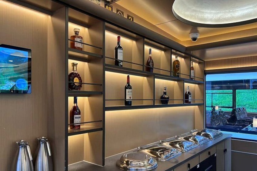 A bar area with shelves of liquor bottles, a TV screen, and a view of the outdoors. 2
