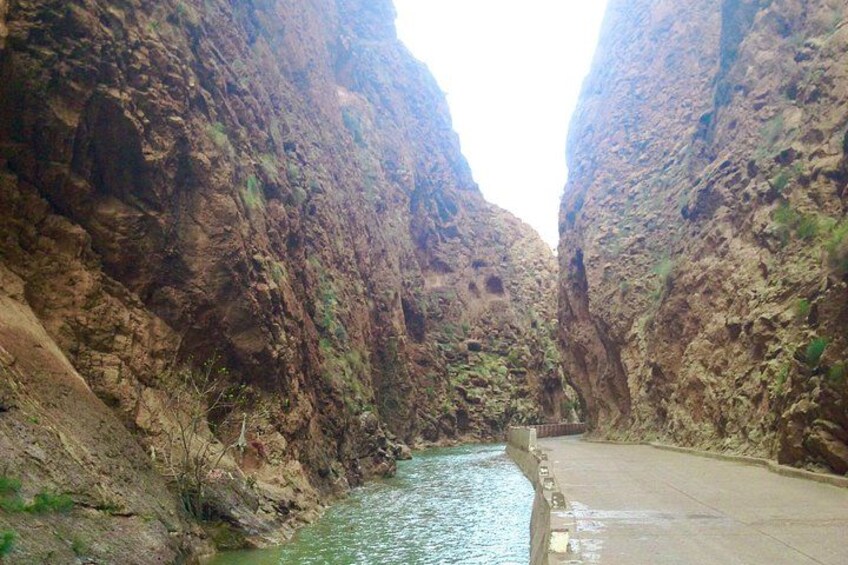 A canyon with a river, rocky cliffs, and a paved road. 2