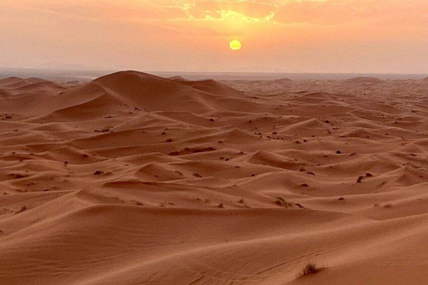 A desert landscape with sand dunes and a setting sun. 3