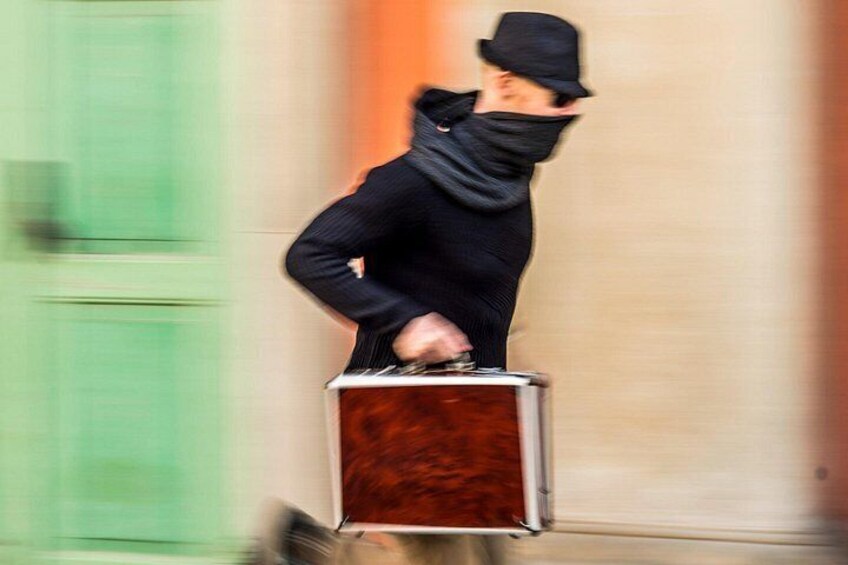 A person in a suit and hat standing on a box. 3