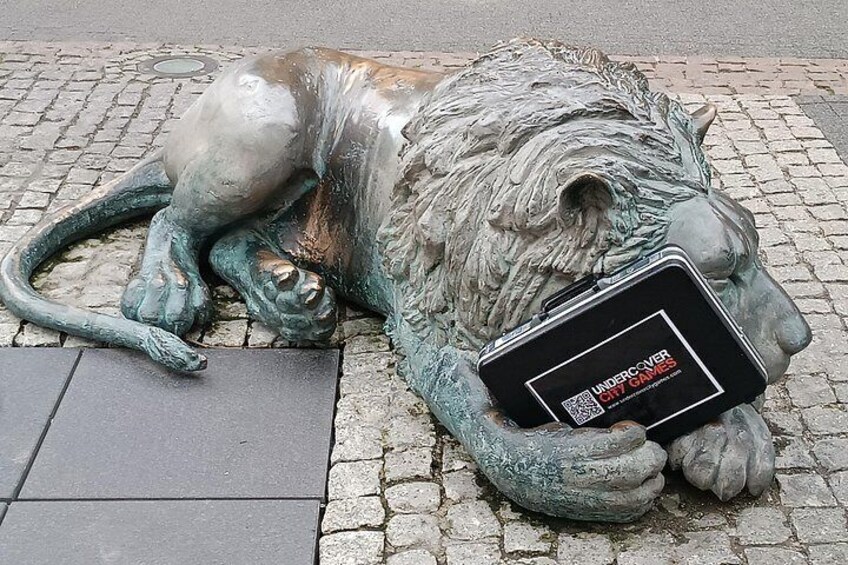 A bronze lion statue lying down with a book. 2