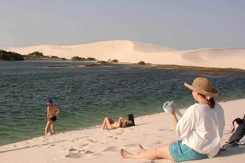 A beach with people relaxing and a person swimming. 4
