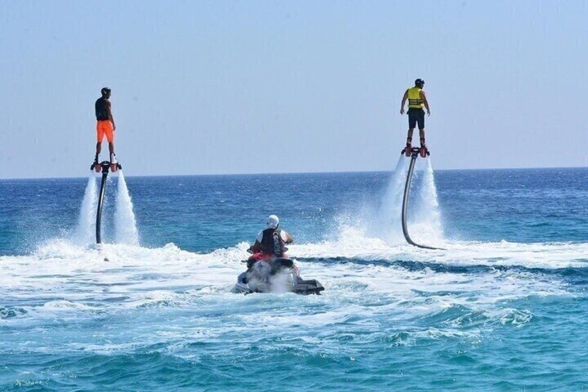 Two individuals performing jet skiing tricks on the water with a jet ski in the background. 5