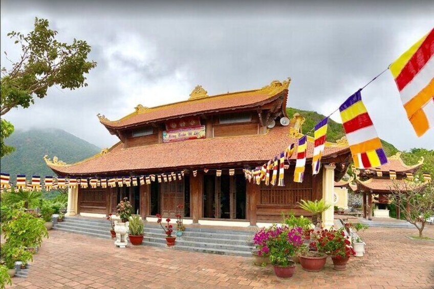 A traditional building with a tiled roof and a signboard, surrounded by potted plants and flags. 3