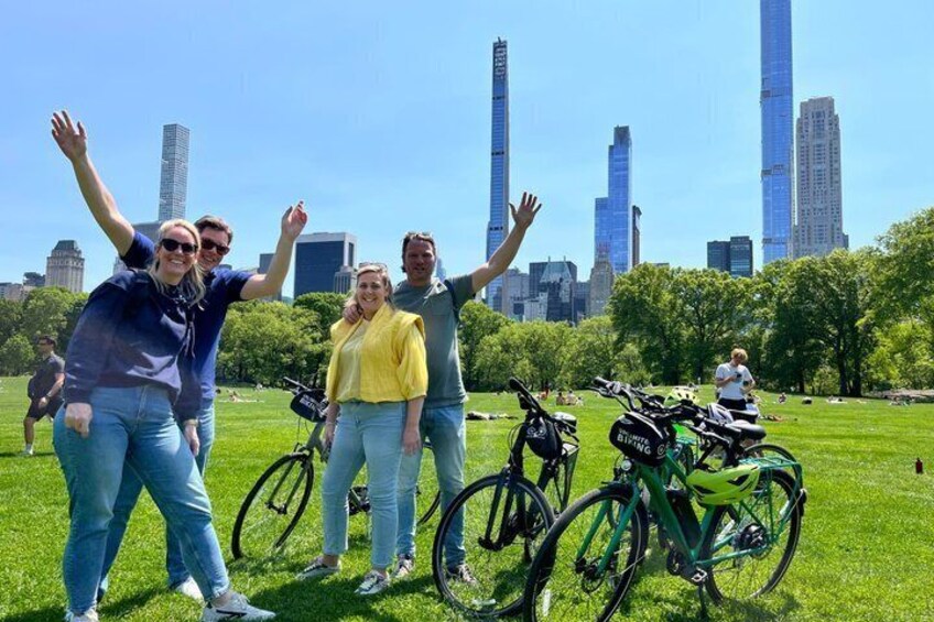 People standing in a park with bicycles, a city skyline in the background. 4