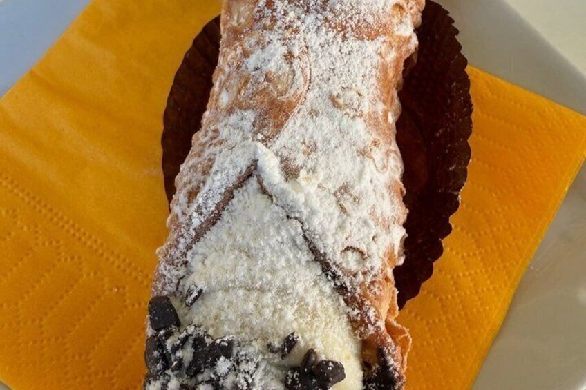 A pastry with powdered sugar and chocolate chips on a yellow napkin. 3