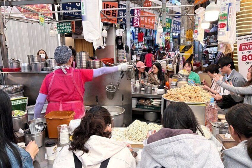 A bustling street food market with vendors serving food to customers. 5
