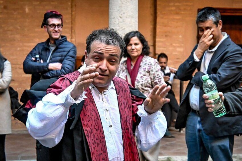 A man in a vest gesturing, with a crowd in the background. 3