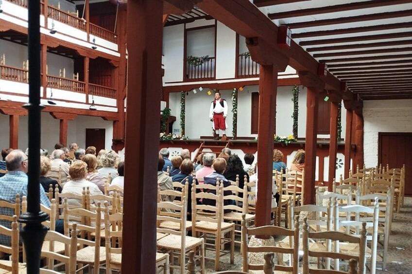 A gathering of people seated on wooden chairs in an outdoor setting with a speaker at a podium. 4