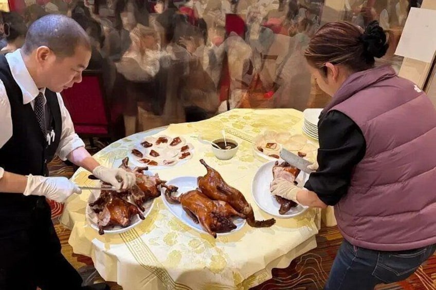 A person carving a roasted duck on a table with a yellow tablecloth. 1