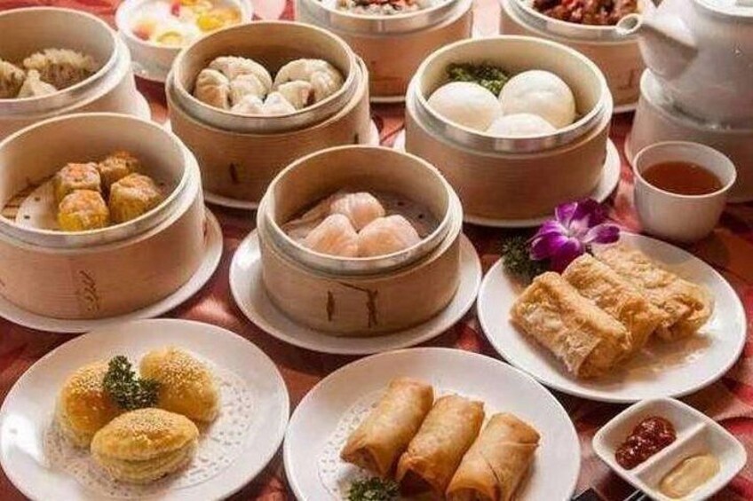 A variety of Chinese dishes including dumplings, spring rolls, and buns on a table. 4