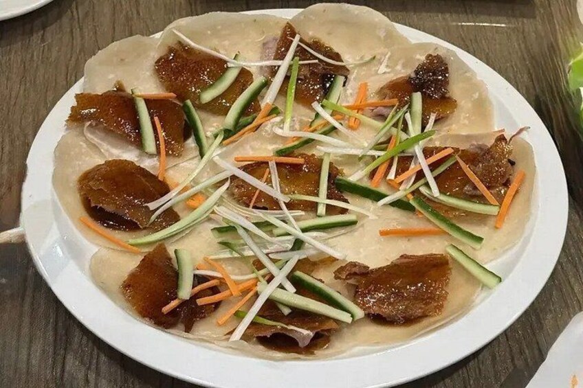 A plate of food with thinly rolled pancakes, meat, and shredded vegetables. 2