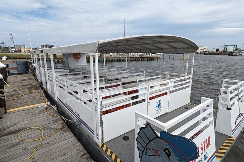 A ferry dock with a covered waiting area, a lifeboat, and a sign with a star logo. 2