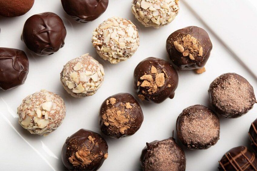 A variety of chocolate truffles on a white plate. 4