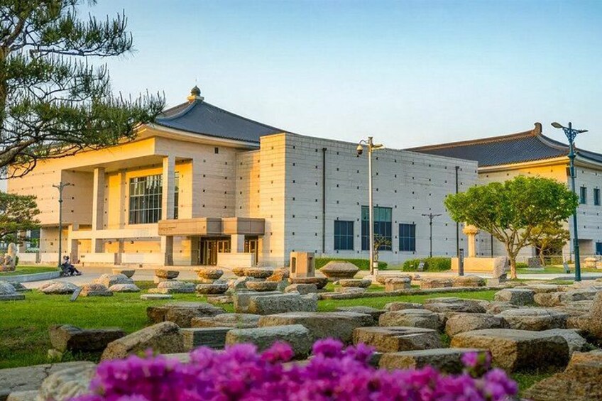 A modern building with a traditional roof, surrounded by a landscaped garden with rocks and flowering plants. 5