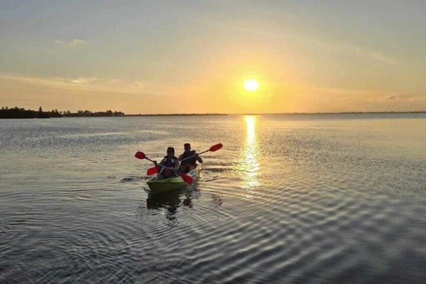 Two people kayaking on a calm body of water during sunset. 2