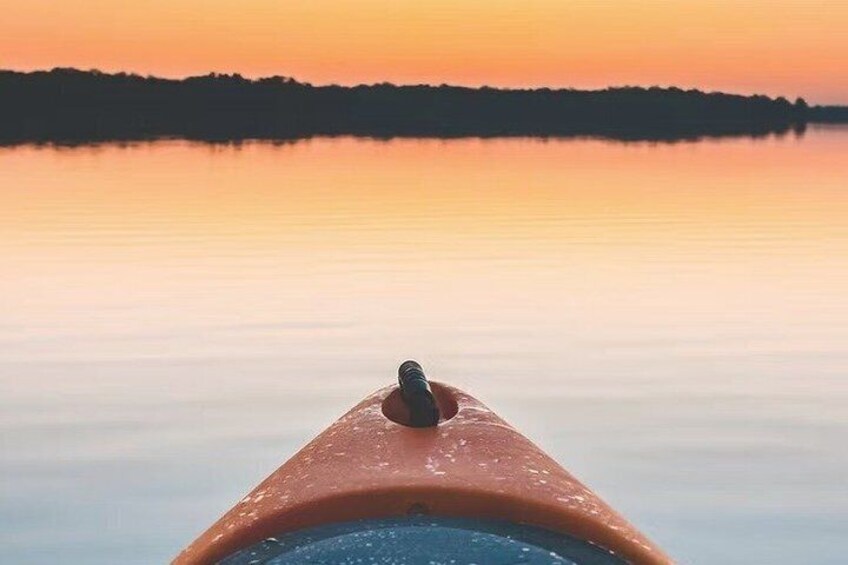 A kayak on calm water with a sunset in the background. 4