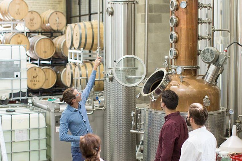 A distillery with large copper stills and wooden barrels in the background. 1