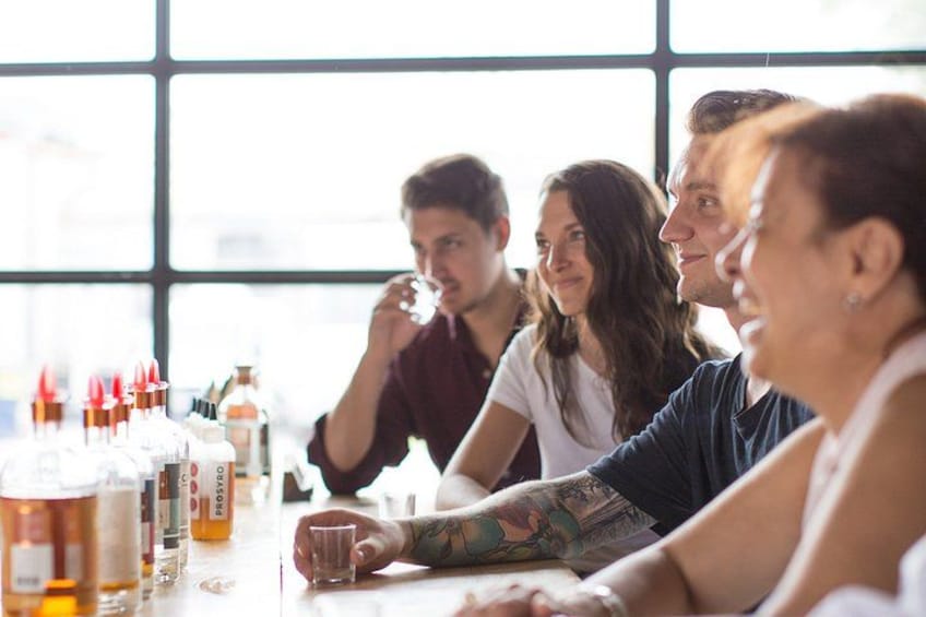 A group of people sitting around a table with various bottles and glasses. 3