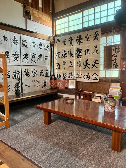 A traditional Japanese room with tatami flooring, a wooden table, and calligraphy on the walls. 3