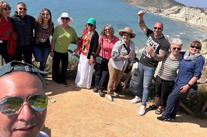 A group of people standing on a cliff overlooking a coastline. 2