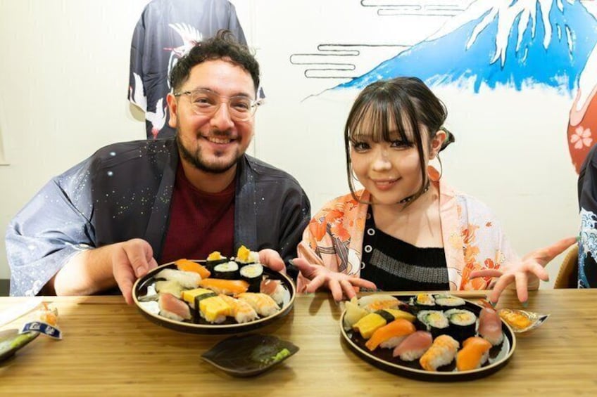 Two people sitting at a table with plates of sushi. 4