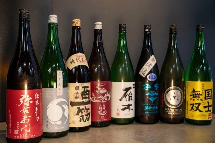 A row of variously colored bottles with labels, some featuring Japanese characters. 2