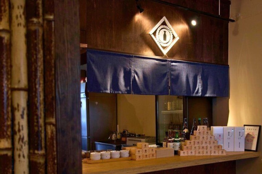 A bar with a blue awning, bottles, and boxes on the counter. 5