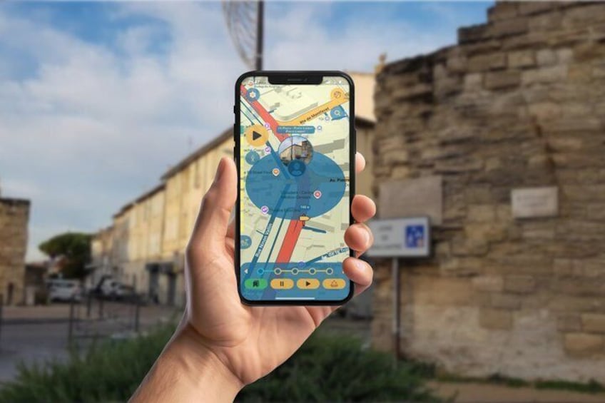 A hand holding a smartphone with a map application, a stone wall, and a sign in the background. 1
