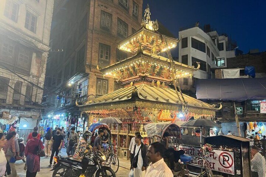 A brightly lit temple with ornate decorations and a crowd of people around it. 2