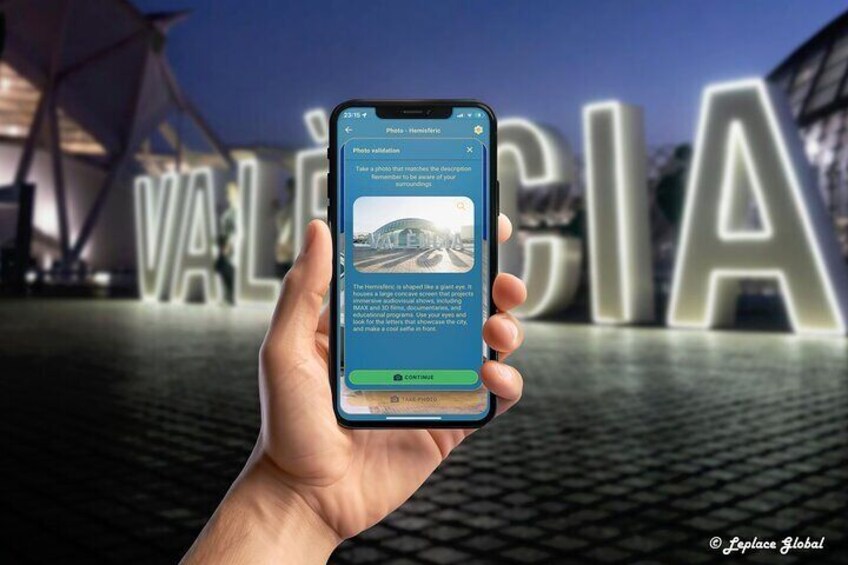 A hand holding a smartphone with a photo validation app open, displaying a photo of a building with the word 'VALENCIA' in the background. 2