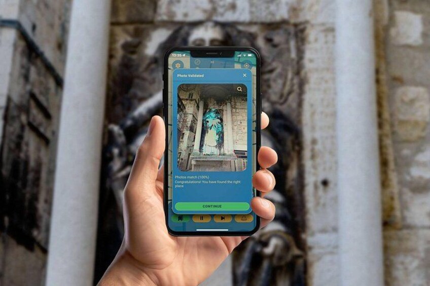 A hand holding a smartphone displaying a photo validation interface with a statue in the background. 3