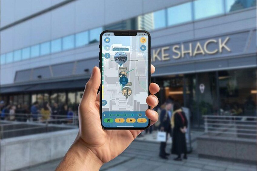 A hand holding a smartphone displaying a map with a location pin, in front of a building with the sign 'KE SHACK'. 5