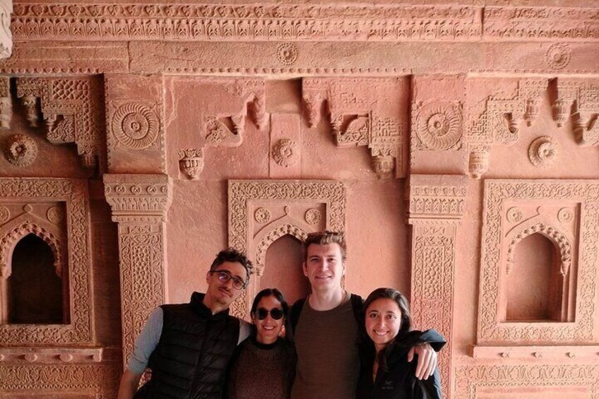 A group of people standing in front of intricately carved architectural structures. 1