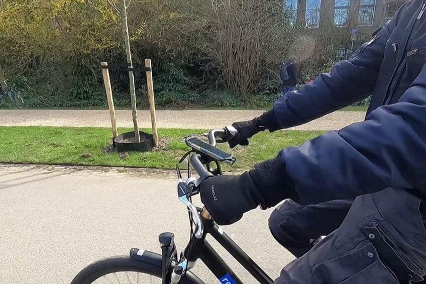 A person riding a bicycle on a paved path with grass and trees in the background. 5