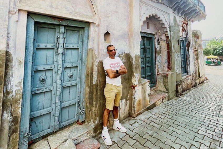 A man standing next to a building with blue doors and a weathered facade. 2