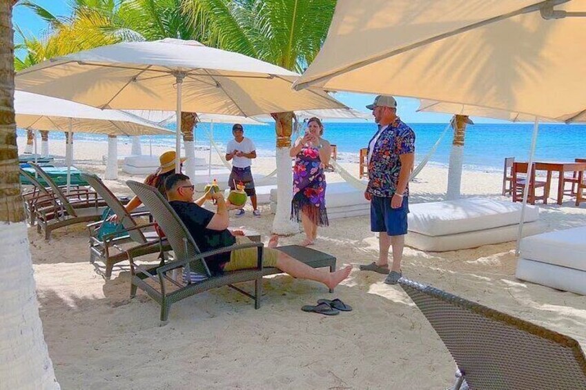A beachside lounge with people relaxing under umbrellas, sun loungers, and beach chairs. 3