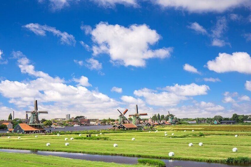 Windmills, a river, and green fields under a blue sky. 1