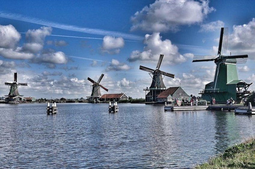 Windmills by a calm water body with boats. 4