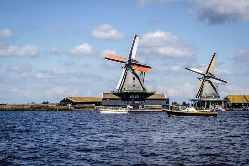A coastal scene with windmills and traditional buildings by the water. 5