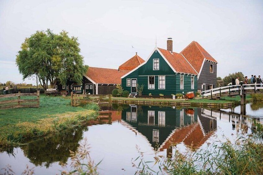 A traditional Dutch house with a red roof, a pond in the foreground, and a wooden bridge. 3