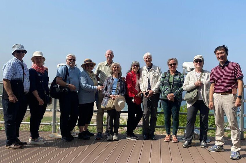 A group of people standing on a wooden deck with a clear sky in the background. 2