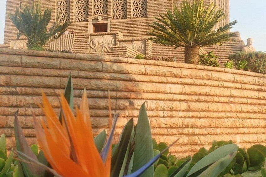 A large, intricately carved stone structure with a staircase leading up to it, surrounded by greenery. 3