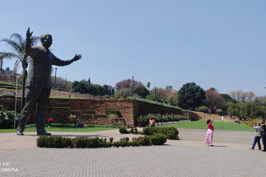 A statue, a brick building, and a park with people. 5