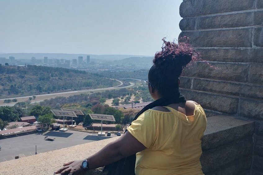 A person overlooking a landscape with a river, buildings, and a hilly terrain. 5