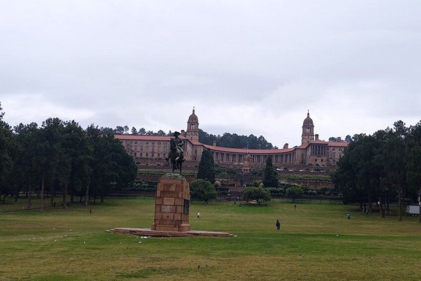 A large building with two towers, a grassy field, and a statue in the foreground. 2