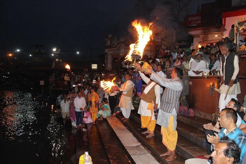 A group of people performing a ritual by the water with flames. 4